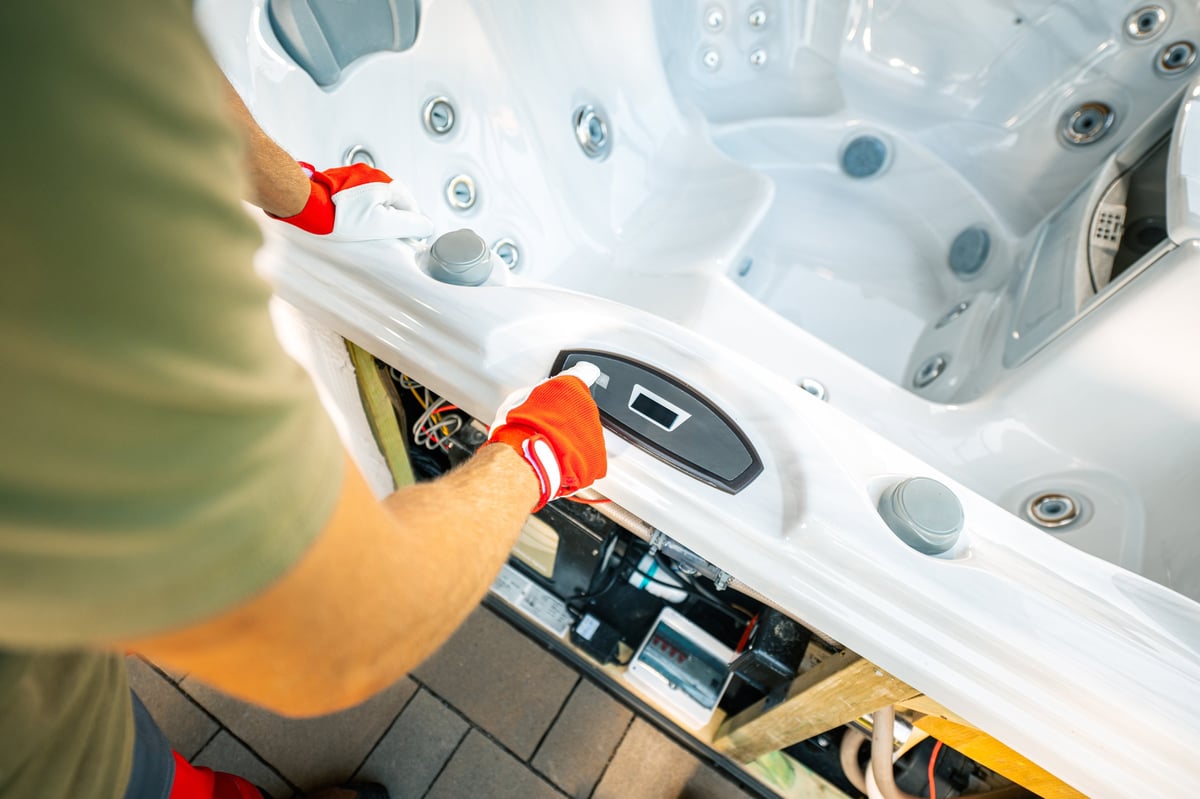 A technician in gloves adjusting the control panel of a hot tub, ensuring proper functionality