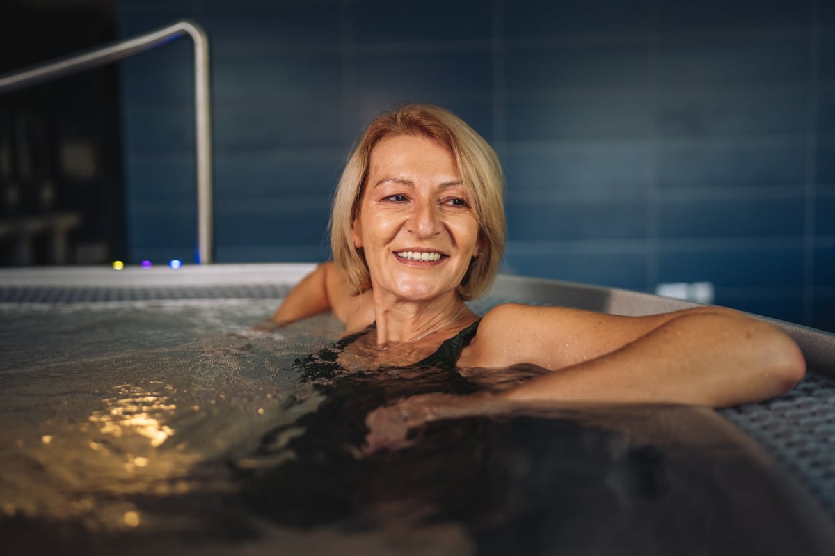 Senior woman relaxing in a warm spa hot tub enjoying therapeutic bubbles